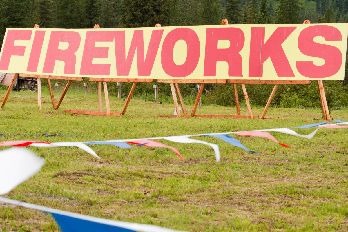 Large roadside fireworks sign advertising a seasonal fireworks stand in a rural area for people learning how to start a fireworks stand