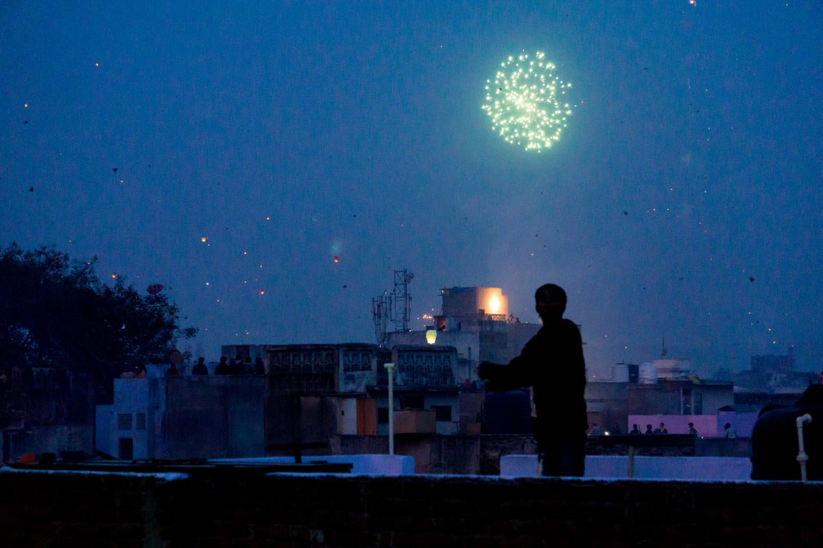 Person watching fireworks over a city skyline while researching firework stand startup cost for a seasonal business