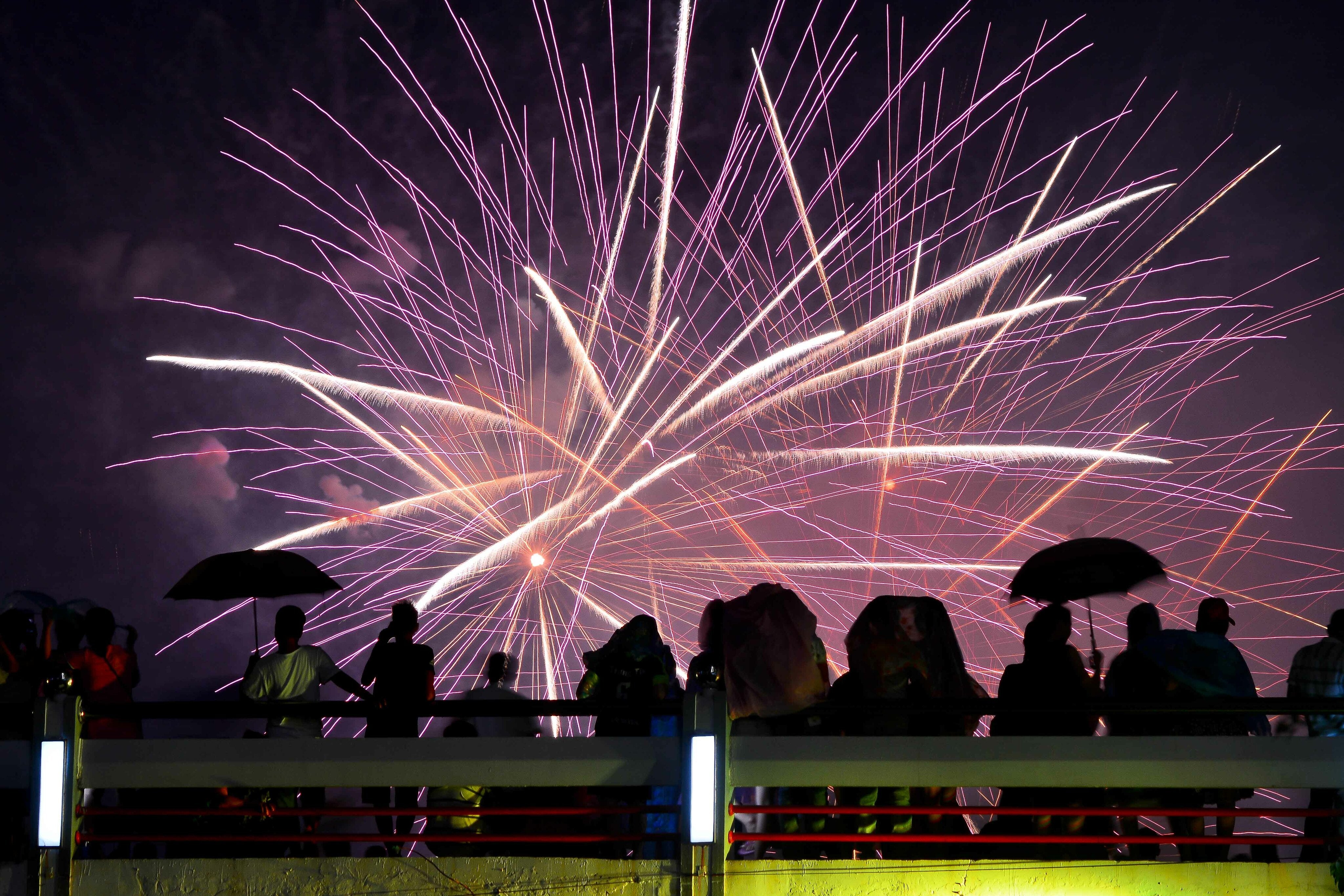 Crowd enjoying a vibrant outdoor fireworks show at night