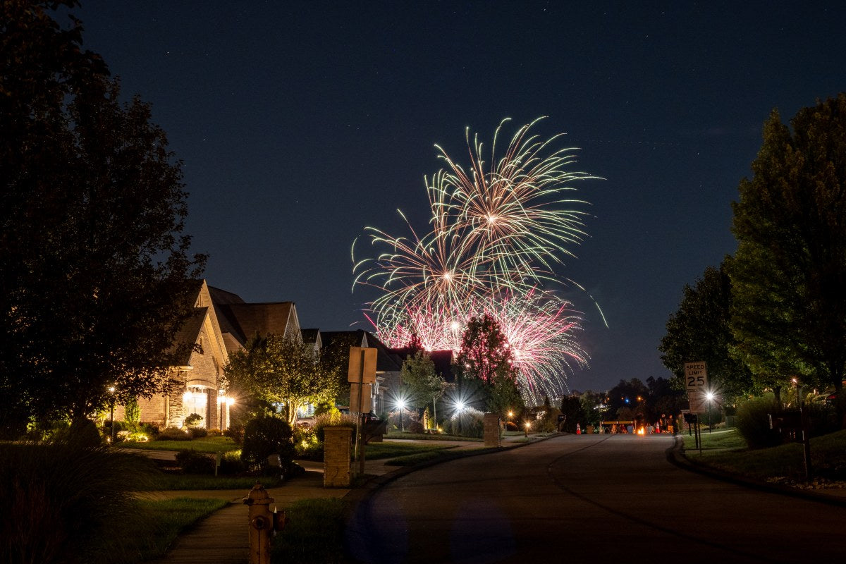 Fireworks exploding over homes at night, illustrating why are people setting off fireworks for holidays and community events
